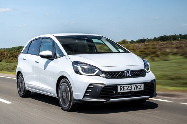 A white Honda Jazz driving on a road on a sunny day in the UK